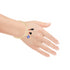 A hand is shown wearing the "Blue Evil Eye Figa Hand Curb Chain with 3 Lucky Charms" bracelet, featuring a gold chain design and adorned with a blue and white evil eye charm, small black and red tassels, and an Azabache charm for extra protection, all against a white background.
